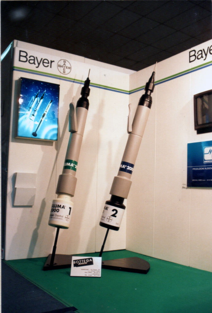 Mockup pubblicitario per fiera. Uno stand di Bayer con ingrandimento di oggetti in mostra.